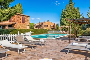 A poolside area with lounge chairs and a pergola. - Apartment Ciclamino Shared Pool & Activities in Tuscany, Montaione, Italy (Montaione)