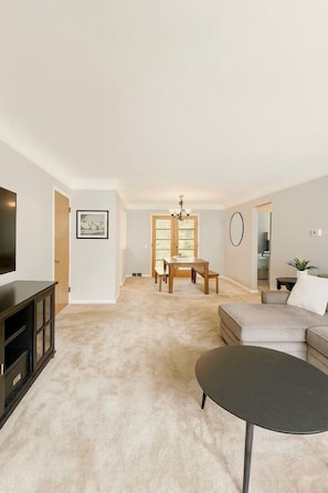 A living room with a TV, a dining area with a table and chairs, and a sofa. - Modern 3BR + Office • Dog-Friendly w/ Fenced Yard (South Euclid)