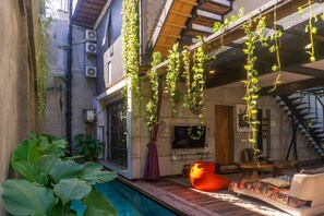 Un espacio moderno con piscina, mobiliario exterior y plantas colgantes.