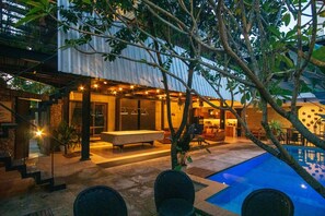 Un área de piscina moderna al aire libre con zona de comedor y espacio de estar cubierto.