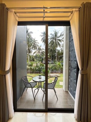 A room with a sliding glass door leading to an outdoor patio with a table and chairs. - DANU COCO Pool Villa (Ko Pha-ngan)