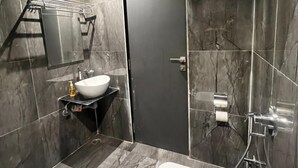 A modern bathroom with a marble floor, a white sink, a towel rack, a toilet, and a shower area. - CR Residency By Glitz Hotels (Mumbai)