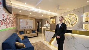 A modern reception area with a blue sofa, a reception desk, and a wall with a floral mural. - CR Residency By Glitz Hotels (Mumbai)