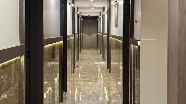 A long, narrow hallway with a shiny marble floor and modern lighting fixtures. - CR Residency By Glitz Hotels (Mumbai)