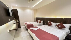 A hotel room with three beds, each with white bedding and red accents, a bedside table, and a wall-mounted TV. - CR Residency By Glitz Hotels (Mumbai)