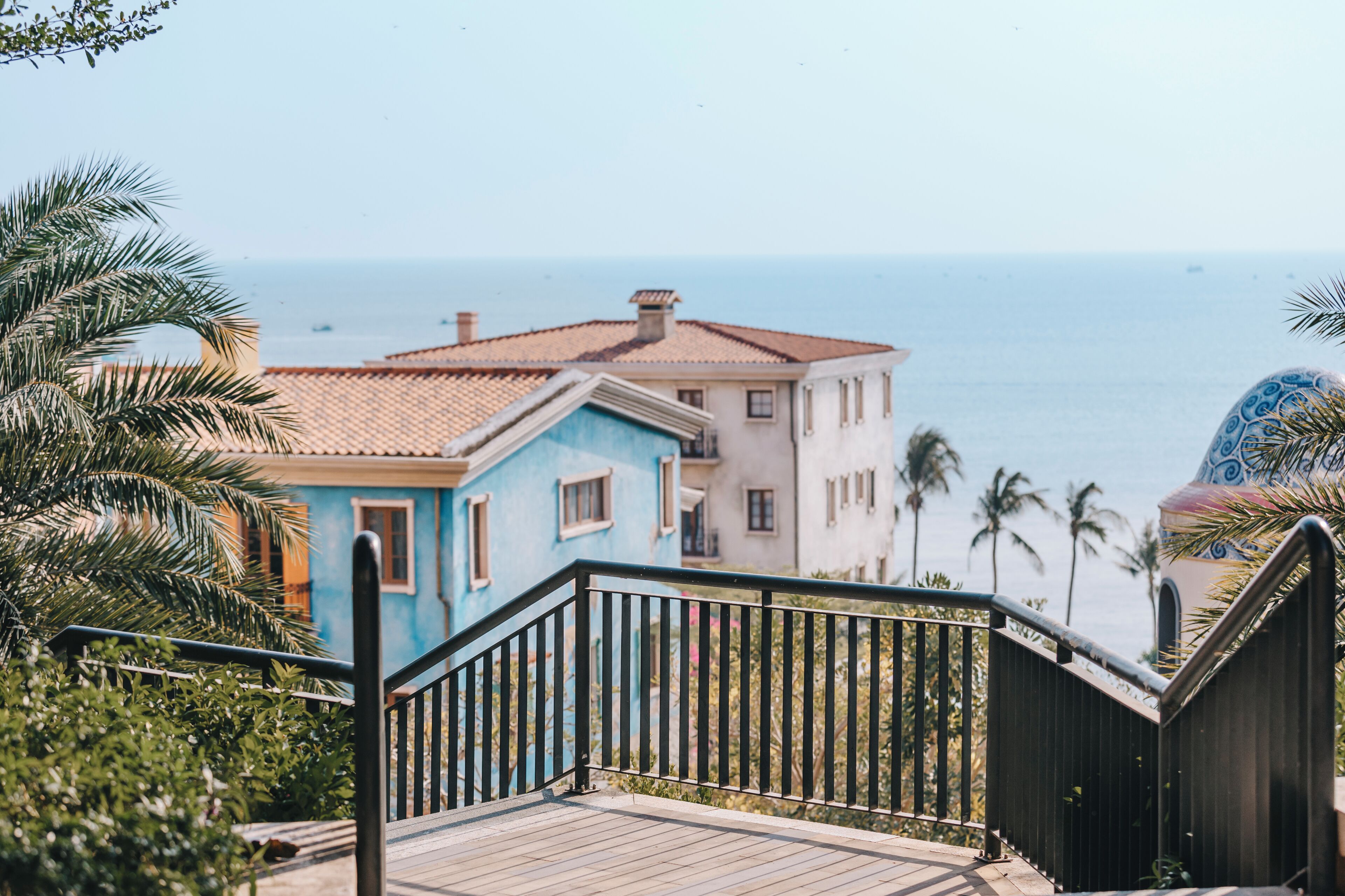 A coastal building with a tiled roof, a wooden deck, and a view of the sea.