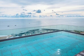 A rooftop infinity pool with a glass railing, overlooking a calm sea and distant shoreline. - The Hill Apartment Phu Quoc Firework (Phu Quoc)