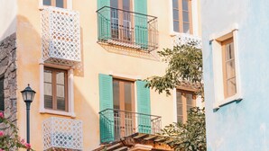 Un edificio de varios pisos con balcones, una escalera de piedra y barandilla de hierro forjado.