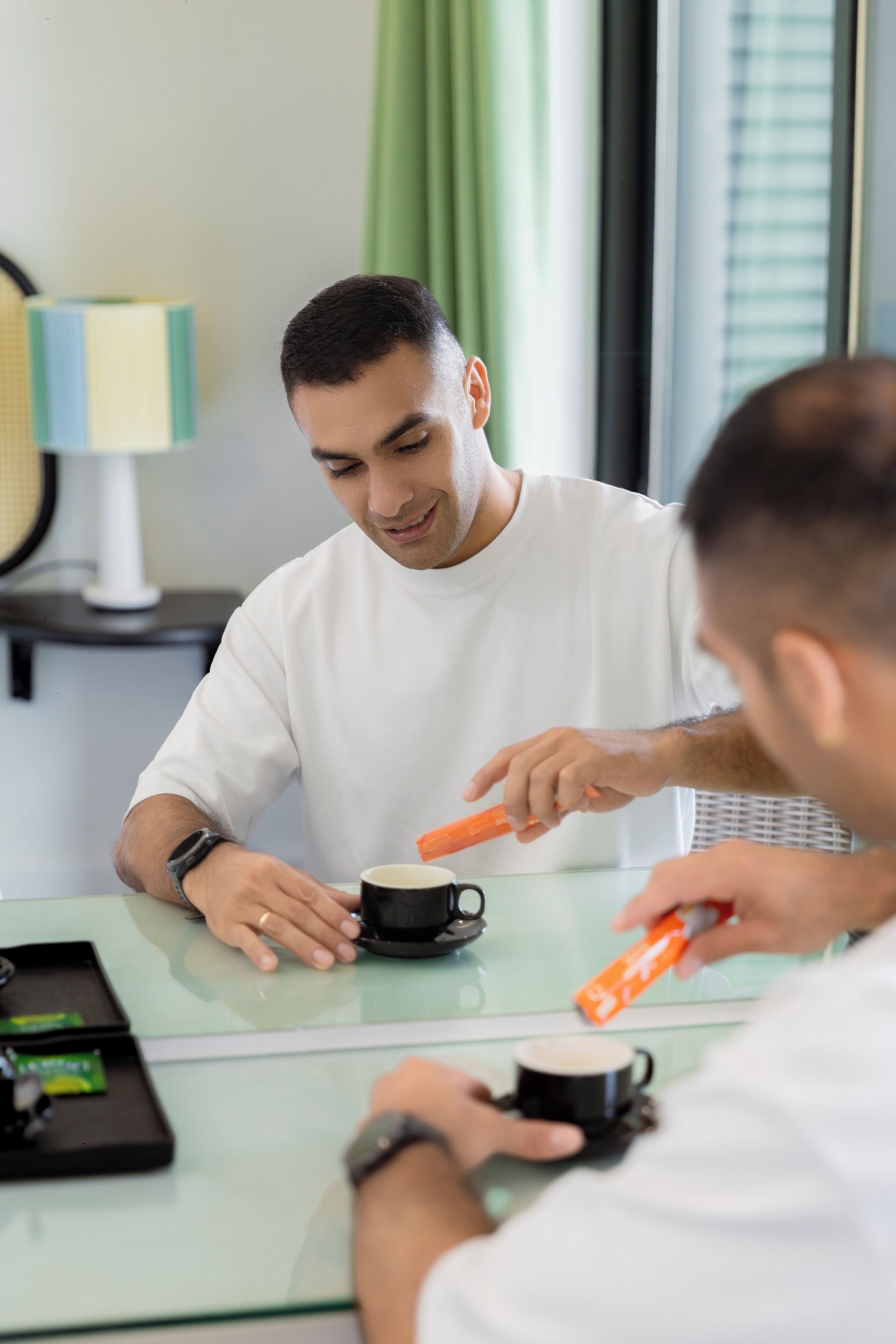Une personne assise à une table, avec une tasse et un téléphone intelligent.