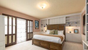 Een slaapkamer met een groot bed, inbouwkasten en een deur met glaspanelen.