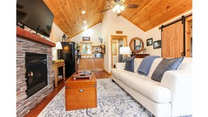Una sala de estar acogedora con chimenea de piedra, una mesa de centro de madera y un sofá blanco con cojines azules.