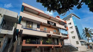 A hotel with a sign reading "HOTELO," featuring a multi-story structure with balconies, a staircase, and a modern facade. - Classic Sri Sai Guru Comfort (Bengaluru)