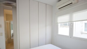 Une chambre à coucher comprenant un lit, une armoire et un appareil de climatisation.