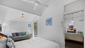 Un dormitorio amplio con una cama grande, ventilador de techo y vistas al balcón.