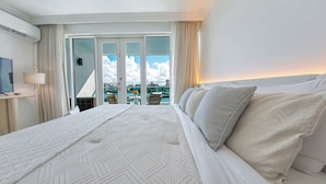 Ein Hotelzimmer mit einem großen Bett, einem Fernseher und Blick auf die Stadt durch die Fenster.