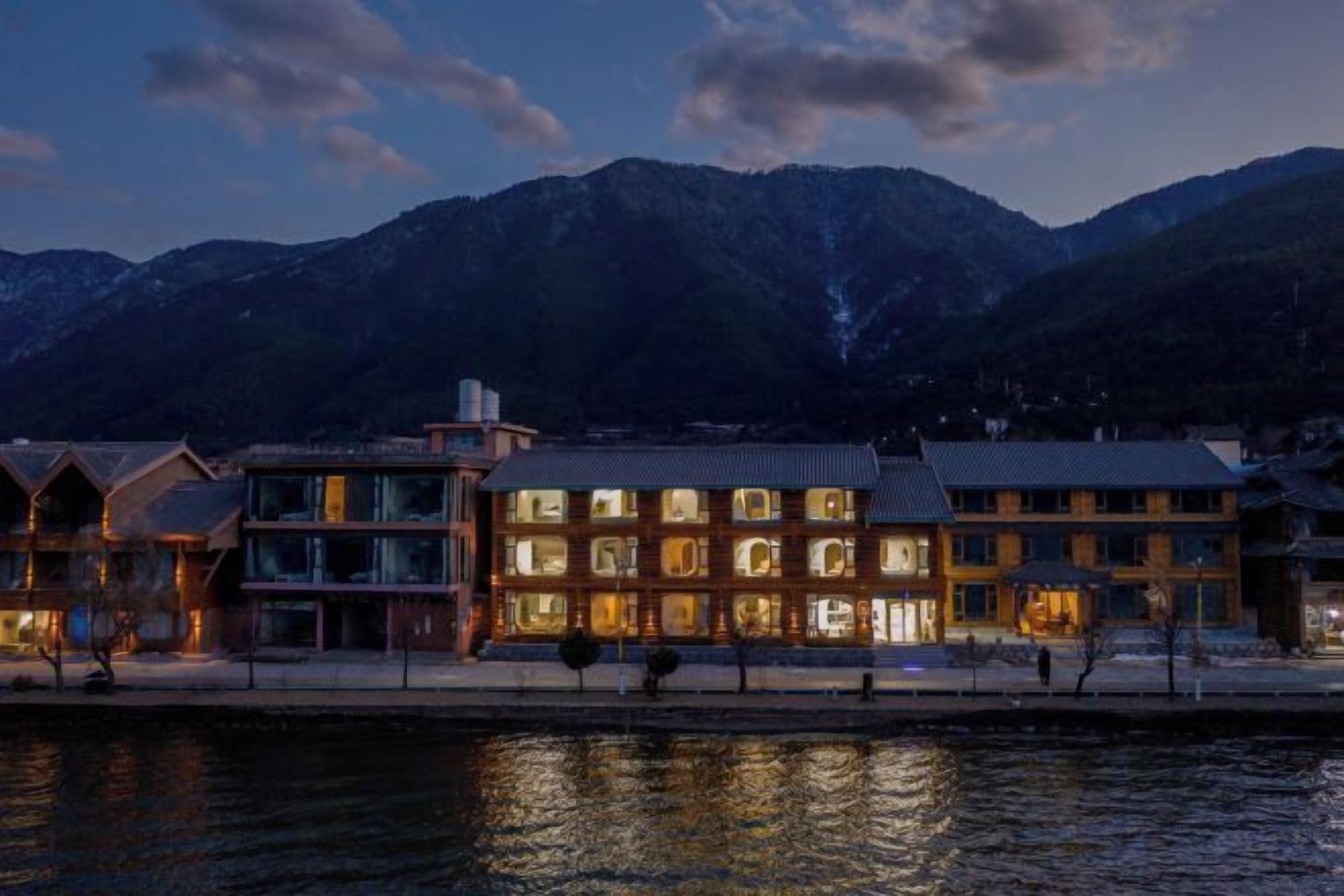 A hotel with multiple buildings, a waterfront, and mountains in the background.