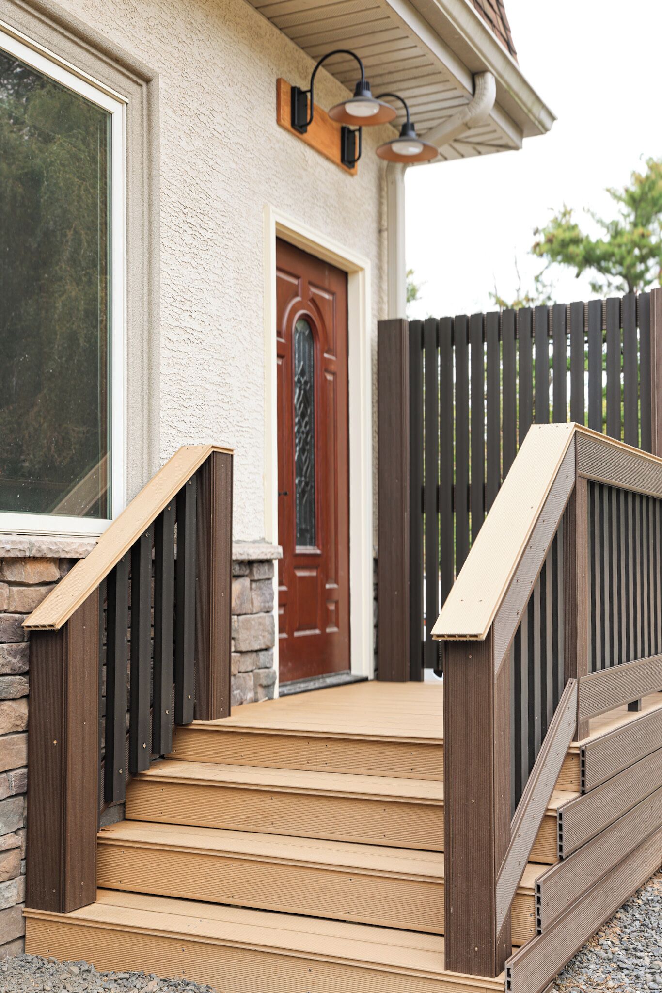 Un escalier en bois menant à l’entrée d’une maison, avec un socle en pierre et une porte en bois.