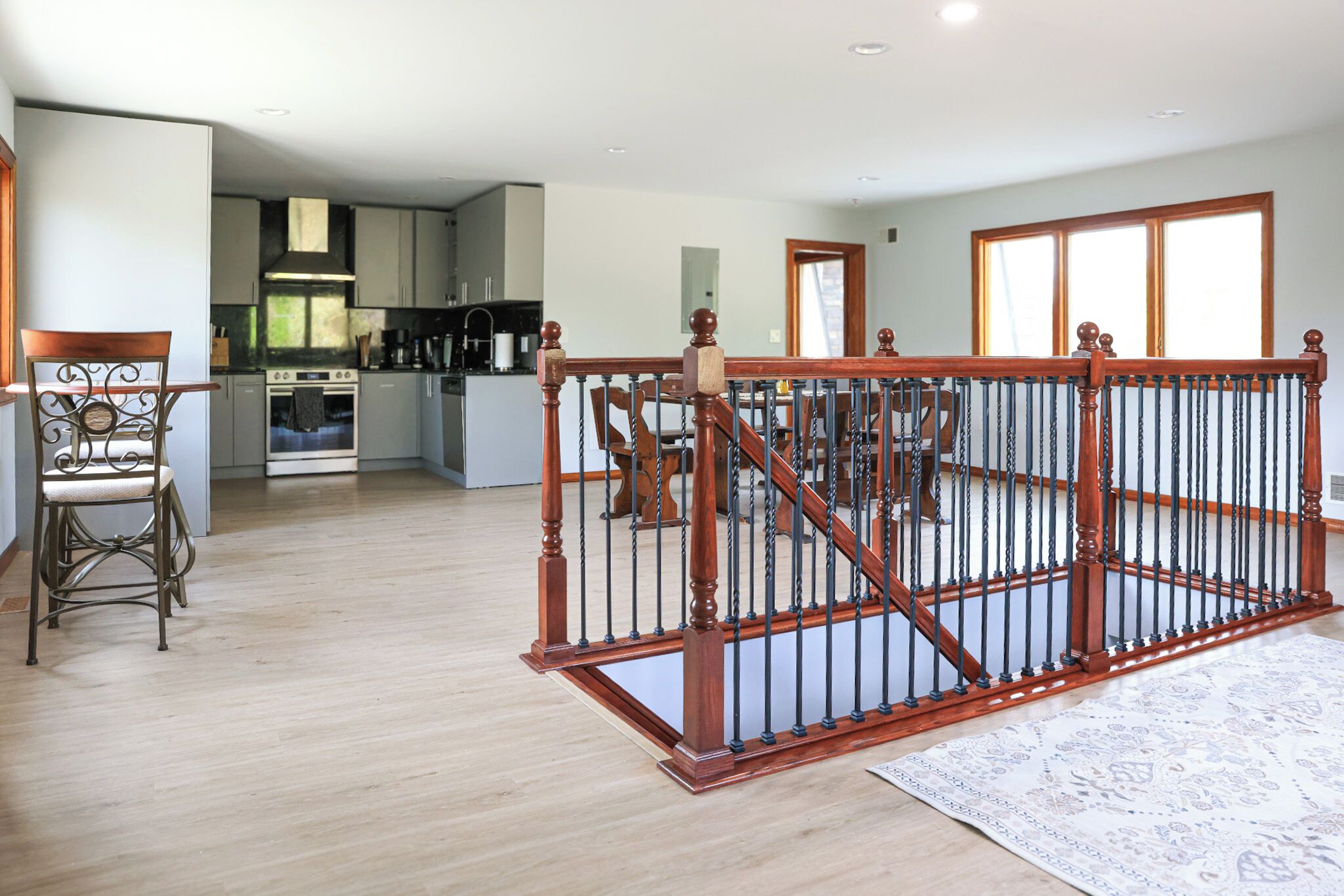 Un vaste espace de vie comprenant un escalier en bois, une table à manger et une cuisine située au fond de la pièce.