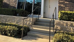 A modern building with a brick facade, large windows, and a set of concrete steps leading to a door. - Cozy 1-bedroom condo loft with fitness room, AC in awesome LA/LAX/Beach (Los Angeles)