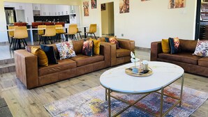 A spacious living area with two brown leather sofas, a round coffee table, and a colorful abstract rug.