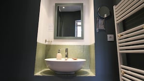 A bathroom with a freestanding bathtub, a mirror above the sink, and a towel rack to the right. - Chambre Tilleul 1 st floor (ST MALO)