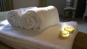 A white towel with a rolled towel and two soap bars on a table. - Chambre Tilleul 1 st floor (ST MALO)