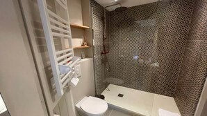 Et badeværelse med toilet, brusebad og tapet.