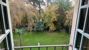 Vista des del balcó amb barana metàl·lica, sobre un jardí ben cuidat amb arbres diversos i gespa.