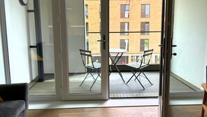 Eine moderne Wohnung mit einer Schiebeglastür, die auf einen Balkon mit Tisch und Stühlen führt.