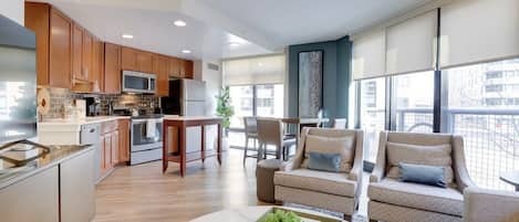 A modern kitchen with wooden cabinets, stainless steel appliances, and a dining area with a table and chairs.