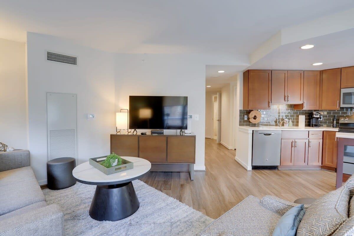 A modern living room with a round coffee table, a grey sofa, and a TV on a cabinet.
