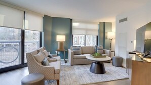 A modern living room with a sofa set, a coffee table, and a dining area. - Sojourn | VA Square | 1 BR (Arlington)