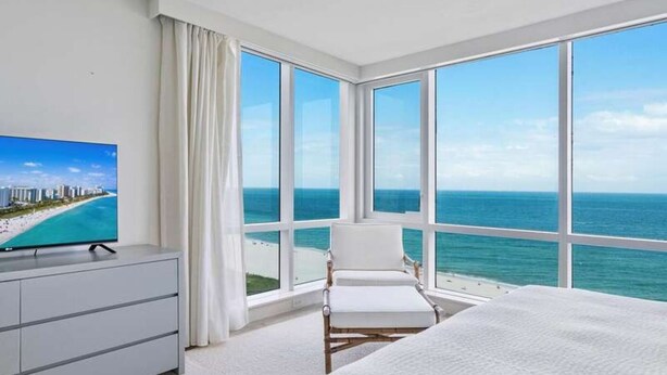 Une chambre d’hôtel dotée d’une grande fenêtre donnant sur la plage et l’océan.