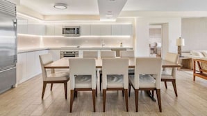 Une cuisine moderne dotée d’un îlot central, d’appareils électroménagers intégrés et d’un coin repas avec six chaises.