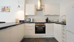 A compact kitchen with white cabinets, a microwave, a stove, and a sink.