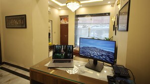 A reception desk with a laptop, a desktop monitor, and a telephone. - Ragam Residency (VARANASI)