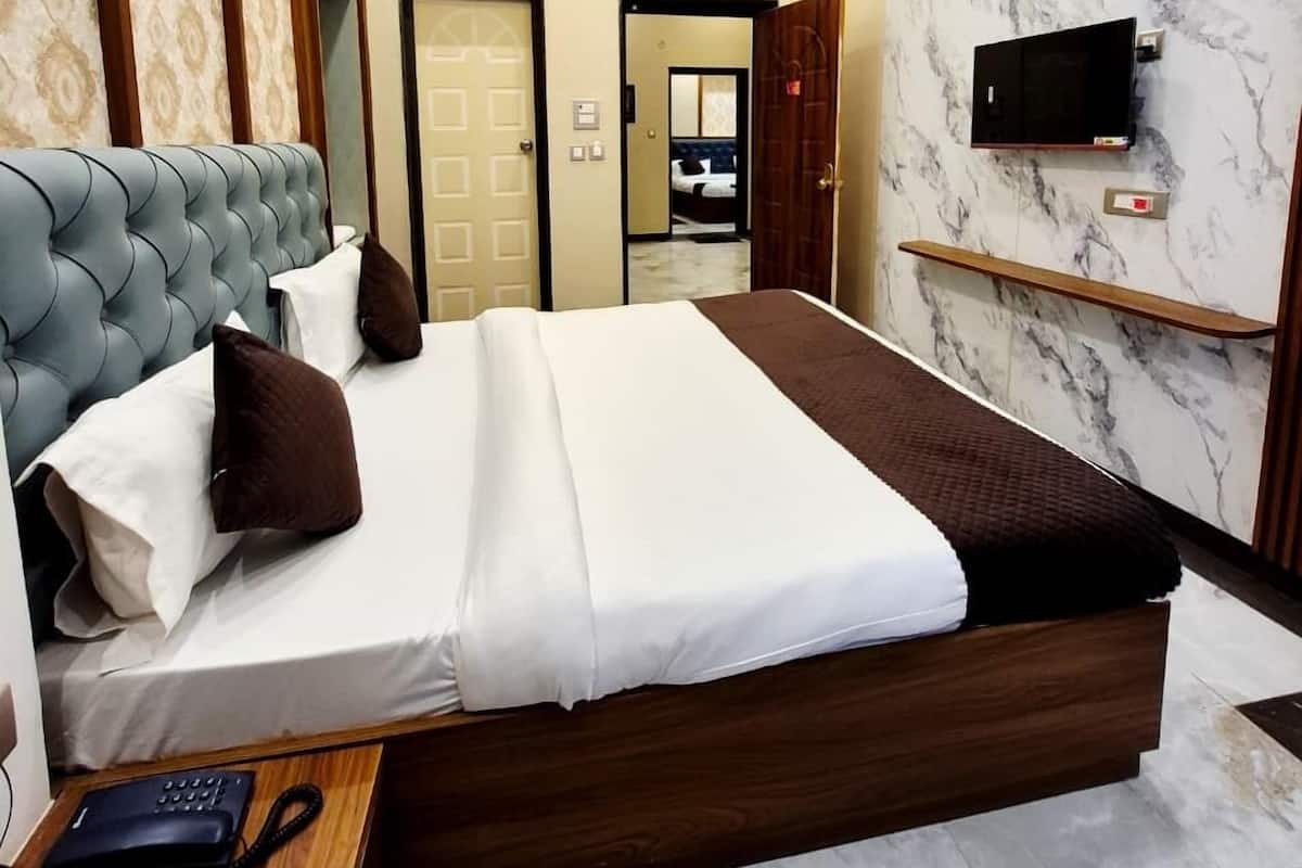 A modern hotel room with a large bed, a ceiling fan, a TV mounted on the wall, and a marble-patterned wall.