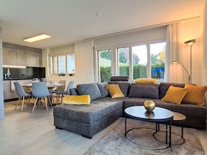 Ein modernes Wohnzimmer mit einer Eckcouch, einem Essbereich und einer Küche.
