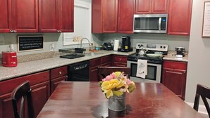 A kitchen with wooden cabinets, a granite countertop, a stainless steel microwave, a stove, and a dishwasher. - Charming 3 bd 2 bath cozy home in Denham Springs with AC and pool (Denham Springs)