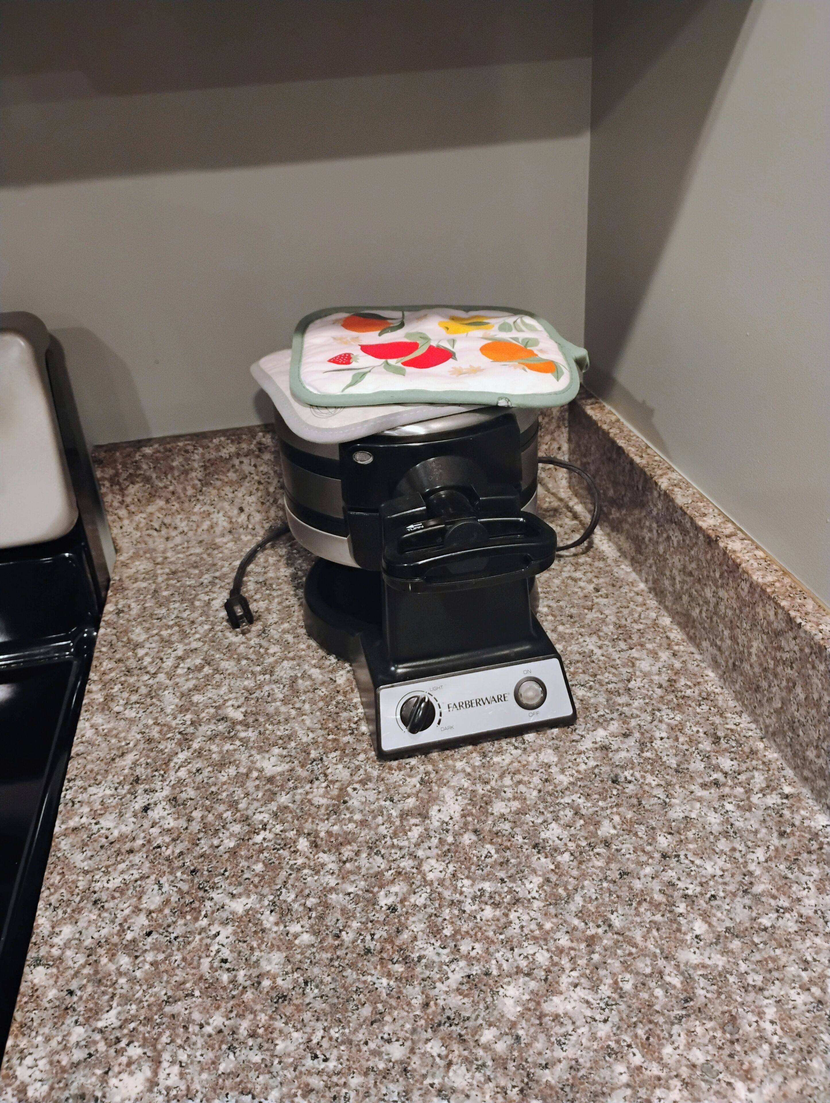 A Farberware waffle maker on a granite countertop.