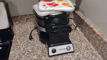 A Farberware waffle maker on a granite countertop.
