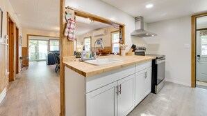 A modern kitchen with a wooden countertop, white cabinets, a stainless steel sink, and a built-in dishwasher. - Lakefront Getaway, 2-bedroom house with kayaks and deck (East Tawas)