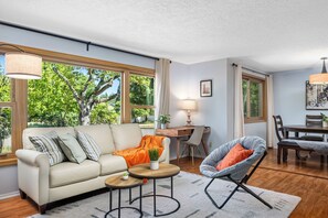 A modern living room with a sofa, armchair, coffee table, and dining area. - 3/2 in Milwaukie - dead end street, free parking! (Milwaukie)