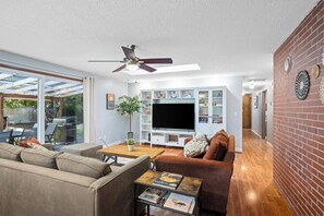 A modern living room with a sofa, coffee table, TV, and a brick wall. - 3/2 in Milwaukie - dead end street, free parking! (Milwaukie)