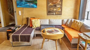 Un salon confortable avec un canapé, une table basse et un téléviseur fixé au mur.