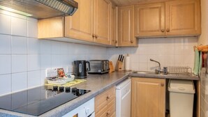 Ett kompakt kök med träskåp, en inbyggd spis, en diskmaskin och en liten arbetsyta.