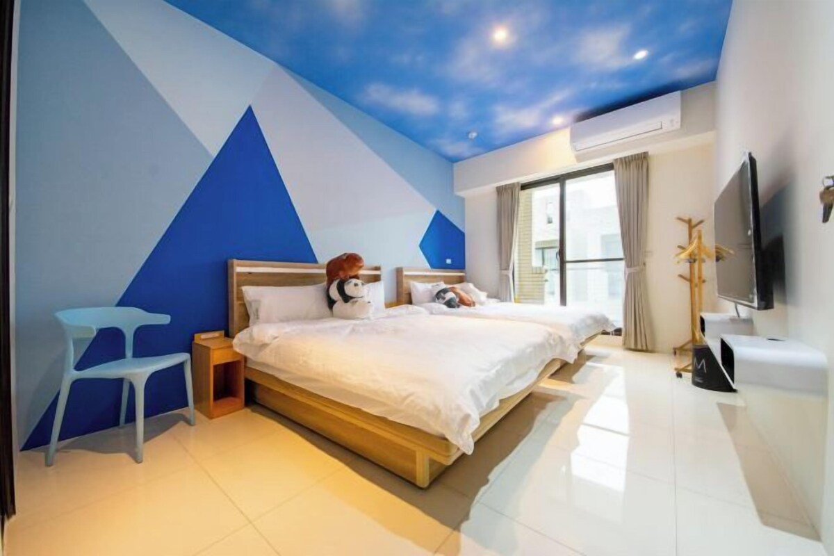 A modern bedroom with a large bed, a nightstand, a TV, and a window with curtains.