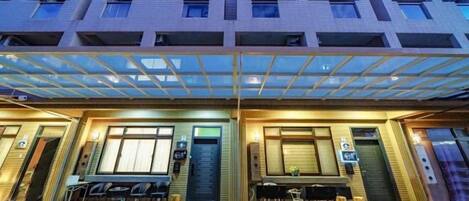 A hotel with a covered entrance, multiple balconies, and a ground-level seating area.