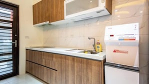 A modern kitchen with wooden cabinets, a microwave, a sink, and a refrigerator. - NEAR HOMESTAY (Yilan)