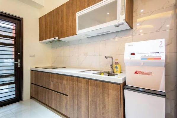 A modern kitchen with wooden cabinets, a microwave, a sink, and a refrigerator. - NEAR HOMESTAY (Yilan)